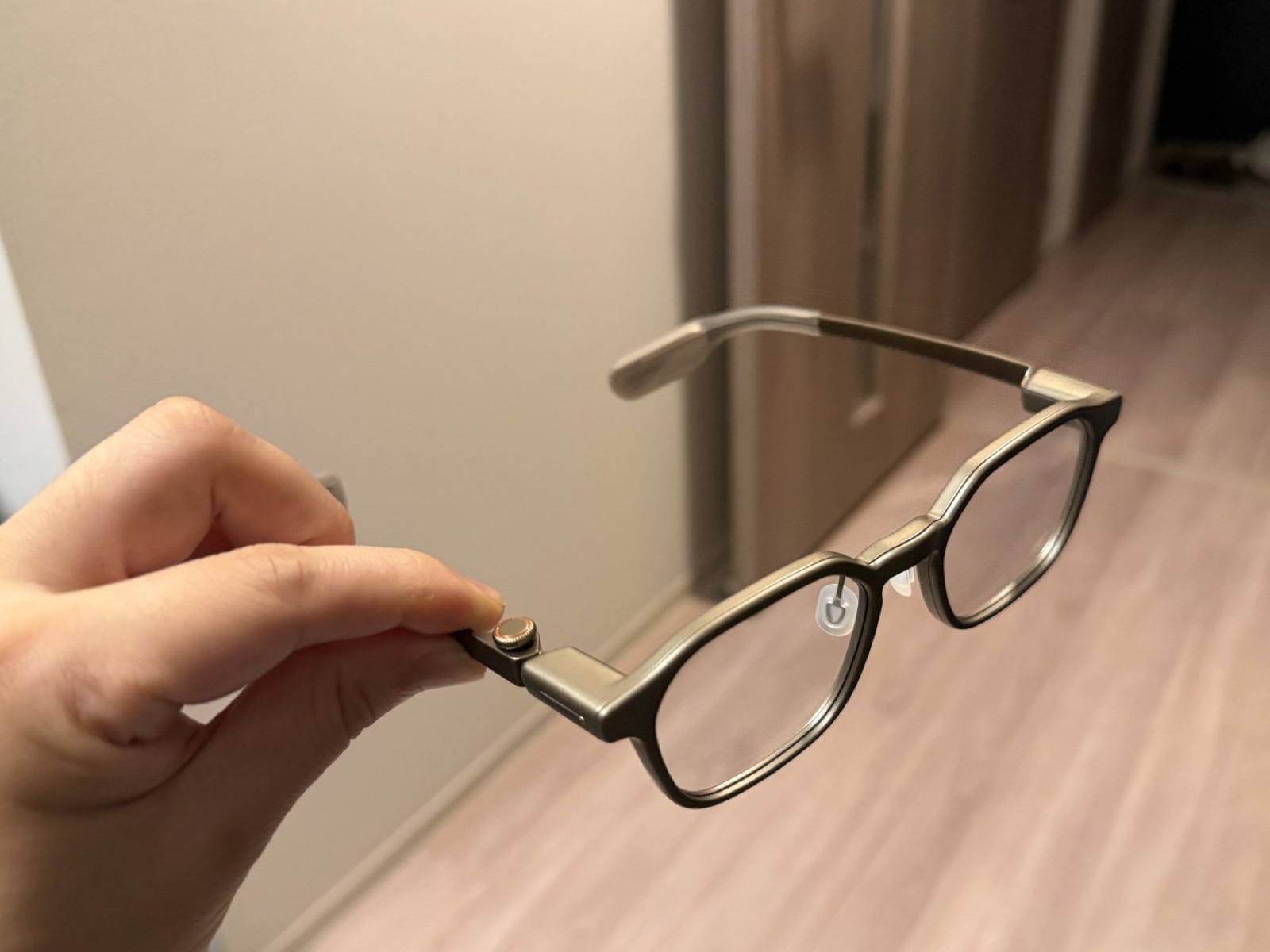 Hands-on photo with a finger beside RayNeo iO’s Smart Crown